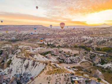 Türkiye 'nin başkenti Kapadokya' nın dağlık arazisinde akşam vakti açık turuncu güneş ışığıyla havada renkli sıcak hava balonları uçuşuyor. Yatay çekim. Yüksek kalite fotoğraf