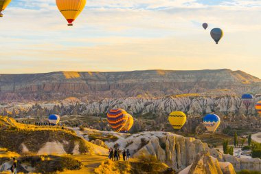 Kapadokya tepelerinde parlak sarı gün ışığında açık gökyüzü ile uçan renkli sıcak hava balonları. Yatay çekim. Yüksek kalite fotoğraf