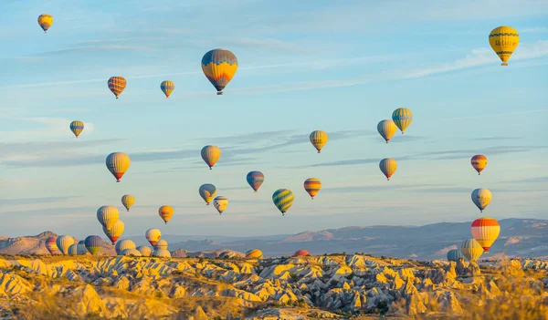 Viele Bunte Heißluftballons Fliegen Strahlend Gelben Abendsonnenlicht Über Die Berglandschaft — Stockfoto