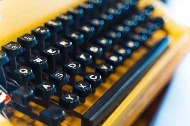 İletişim ve teknoloji konsepti evrimi. Siyah tuşlu, iyi korunmuş sarı daktilonun yakın plan çekimi. Ön plana odaklan. Arka plan bulanık. Yüksek kalite fotoğraf