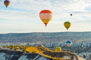 13.10.2022. Kapadokya, Türkiye. Gökyüzünde yüzen renkli hava balonlarının nefes kesici manzarası ve güneş doğarken arka planda kayalık Cappadocias kayalıkları ve muhteşem manzara. Yüksek kalite fotoğraf
