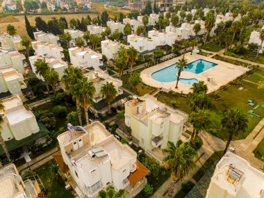 Sıranın ilerisindeki modern beyaz evler ve Türkiye 'deki palmiye ağaçlarıyla çevrili büyük bir havuz. Yüksek kalite fotoğraf