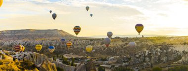 Sıcak hava balonlarından oluşan hava manzarası güneş doğarken Cappadocia 'daki kayalık arazide turneye çıkıyor. Yüksek kalite fotoğraf