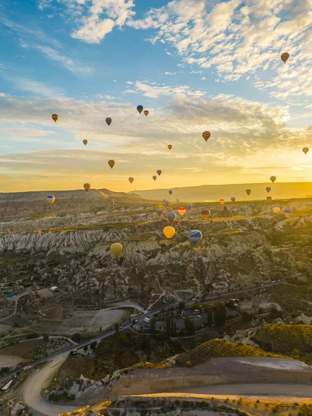 土耳其卡帕多西亚多山的城市景观 各种五彩缤纷的热气球在空中飘扬 明亮的黄昏时分 垂直室外拍摄 高质量的照片 — 图库照片