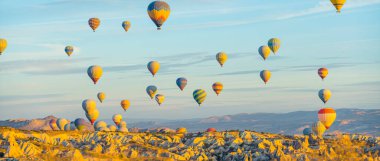 Geniş panoramik çekim. Bir sürü renkli desenli sıcak hava balonu güzel ve alışılmadık Türk kasabası üzerinde uçuyor. Cappadocia 'da balon festivali. Yüksek kalite fotoğraf