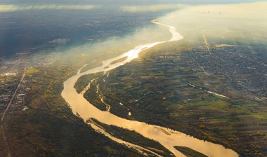 Güzel Vistula Nehri Varşova 'yı ikiye bölüyor. Uçaktan hava perspektifi. Sonbahar sabahı, şehrin üzerinde yumuşak güneş ışığı ve sis vardı. Yüksek kalite fotoğraf