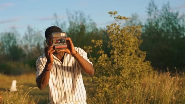 Молодой Взрослый Чёрный Мужчина Поле Фотографирует Своих Друзей Помощью Винтажной — стоковое видео