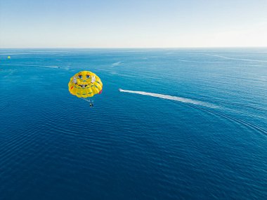 Okurcalar, Alanya, Türkiye. Hız tekneleriyle geniş mavi Akdeniz 'in insansız hava aracı görüntüsü ve paraşütle denizin üzerinde uçan bir insan. Yüksek kalite fotoğraf