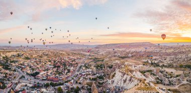 Nevsehir, Goreme, Kapadokya 'daki peri bacalarında renkli sıcak hava balonları uçuşuyor. Muhteşem panoramik dron görüntüsü. Yüksek kalite fotoğraf