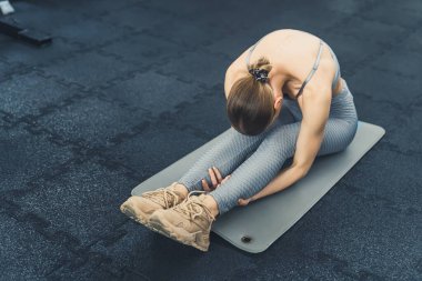 Spor salonundaki yorucu egzersizden sonra esneyip eğilen 20 'li yaşlarda güzel, beyaz bir kız. Uzun menzilli çekim. Yüksek kalite fotoğraf