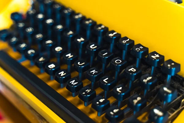 Closeup shot of black push-buttons with white letters of an old-fashioned typewriter in yellow color. Communication before computers and smartphones. Technology evolution. High quality photo