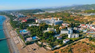 Palmiye ağaçlarıyla çevrili oteller, havuzlar ve plajların yükselen manzarası, yaz tatilleri için en iyi yer, Okurcalar, Türkiye. Yüksek kalite 4k görüntü