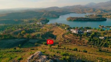 Yüksekten dalgalanan Türk bayrağı ve arka planda mavi göl, Türkiye. Yüksek kalite 4k görüntü