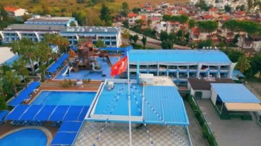 Otelin açık mavi renkli ve havuz kenarlarında Türk bayrağı dalgalanan manzarası, Okurcalar, Türkiye. Yüksek kalite 4k görüntü