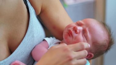 Annelik kavramı. Gri kolsuz tişörtlü beyaz annesi tarafından tutulan sevimli, uyuyan bir bebeğin portresi. Arka plan bulanık. Yüksek kalite 4k görüntü