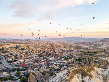 Nevsehir, Goreme, Kapadokya 'daki peri bacaları vadisinde uçan renkli sıcak hava balonları. Yeraltı şehri ve balonlu turizmin muhteşem panoramik görüntüsü. Yüksek kalite
