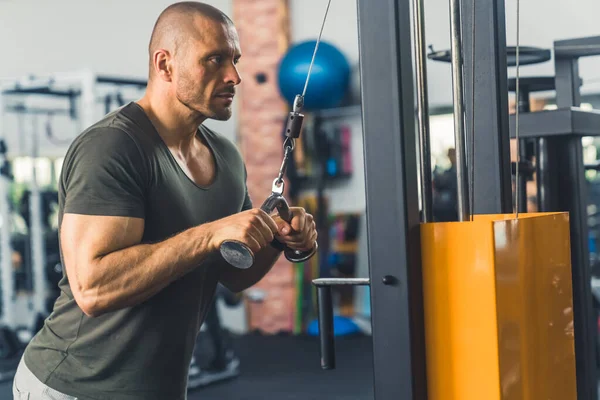 Private male caucasian trainer doing arm exercises at gym using professional equipment. Focus and dedication. Leisure time activities. High quality photo