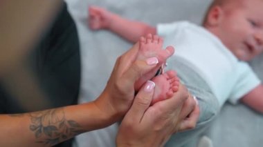 Bebek ayak masajı. Rahatlama zamanı. Tırnakları bakımlı, beyaz tenli, tanınmayan birinin elleri bebek oğluna masaj yapıyor. Yüksek kalite 4k görüntü