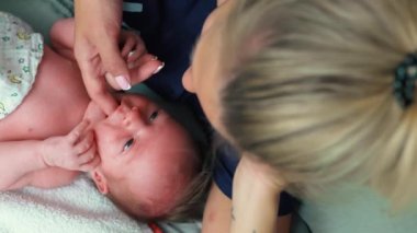 Sarışın, beyaz bir anne bebeğinin küçük ağzına parmağını sokuyor. Diş büyümesi. Büyüme ve çocukluk kavramı. Yüksek kalite 4k görüntü