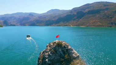 Hindi. Türkiye 'deki Oymapinar Gölü' nün muhteşem hava manzarası, mavi ve tatlı su dev dağlar ve kayalıklarda bir Türk bayrağı. Yüksek kalite 4k görüntü