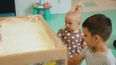 Anaokulundaki çocuklar için yaratıcı aktiviteler, selofan kutusuna elleriyle resim yapan küçük kız ve oğlan. Yüksek kalite 4k görüntü