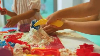 Çocuklar anaokulundaki kinetik kumda plastik figürlerle oynuyorlar. Yüksek kalite 4k görüntü