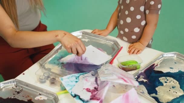 Νεαρός Δάσκαλος Που Βοηθά Παιδιά Ζωγραφίσουν Ένα Τραπέζι Γεμάτο Χρώματα — Αρχείο Βίντεο