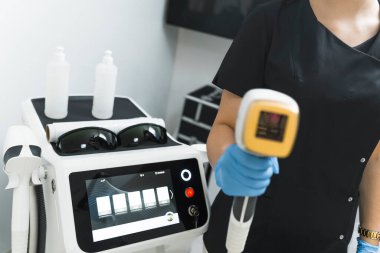  Çeşitli vücut bölgelerindeki saç büyümesini azaltan lazer tedavisi için profesyonel ekipman. Beyaz tenli güzellik uzmanının yanındaki bar lazer makinesi. Yüksek kalite fotoğraf