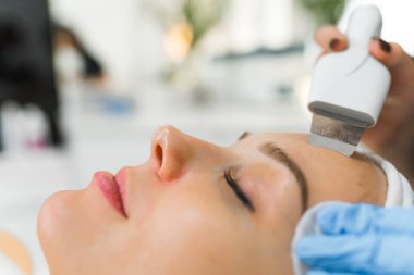 Kapalı gözlü, güzel beyaz bir kadının yüzünde mikro dermabrüksiyon spa tedavisinin bulanık arkaplanlı arka planına sahip aşırı kapalı çekim. Yüksek kalite fotoğraf