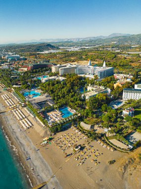 Türkiye 'nin Ocurcalar kentinin sahil kıyısındaki zengin tatil beldelerine ait kuş bakışı manzaralı arka planda dağlar var. Parlak yaz güneşi. Turistik bir yer. Dikey çekim. Yüksek kalite fotoğraf