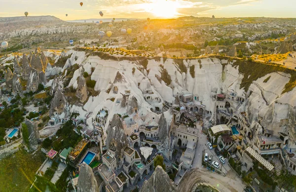 在土耳其卡帕多西亚 从空中俯瞰着被雕刻成岩石山的城镇 热气球在远方飞舞 明亮的黄色阳光 侧向射击 高质量的照片 — 图库照片