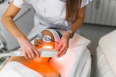 Güzel Asyalı genç bir kadın en sevdiği spa merkezinde termokaldırma tedavisi sırasında tanınmayan beyaz bir güzellik uzmanı tarafından sahnelendi. Koruyucu teçhizat ve kaplıca. Yüksek kalite fotoğraf