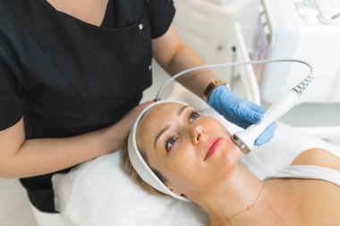 En sevdiği SPA salonunda mikro dermabrüksiyon işlemi sırasında 30 'lu yaşlarında güzel beyaz bir kadın. Siyah üniformalı tanınmayan profesyonel kozmetikçi. SPA iç mekan ve ekipman. Yüksek kalite