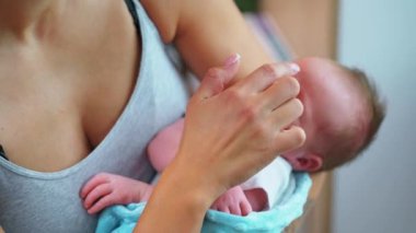 Kapalı mekanda, Avrupalı sıradan giyinmiş annesinin yeni doğmuş bebeğini kucağında tutarken çekilmiş. Arka plan bulanık. Yüksek kalite 4k görüntü