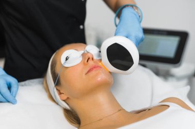 Profesyonel SPA termokaldırma prosedürü. En sevdiği spa 'da termokaldırma tedavisi sırasında koruyucu gözlüklerle kaplanmış 30' lu yaşlarında beyaz bir kadının yakın plan portresi.