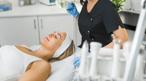 Preparation for SPA treatment. Microdermabrasion procedure. Middle-aged clear-skinned caucasian blonde woman in white tank tip lying down on her back with closed eyes waiting for SPA treatment. High