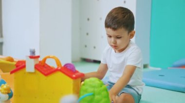 Sevgili küçük çocuk yerde oturuyor ve araba sürüyor, anaokulu konsepti. Yüksek kalite 4k görüntü