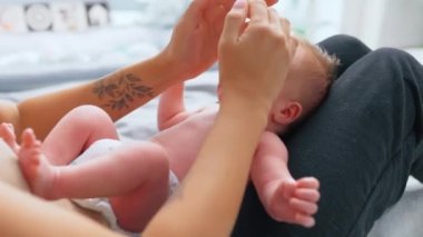 Kolunda nazik bir bitki dövmesi olan tanınmayan beyaz bir insan, anne babaların dokunmasına alışabilsin diye bebek çocuğa yavaşça dokunuyor. Yüksek kalite 4k görüntü