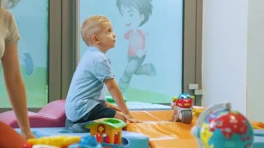 Sarışın küçük bir çocuğun oyun odasında bisikletle oynaması, çocuk aktiviteleri konsepti. Yüksek kalite 4k görüntü