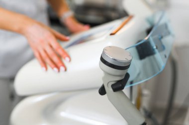 Kamera ön planda profesyonel SPA tedavi makinesini ve arka planda ayarları ayarlayan beyaz uzman kozmetik uzmanını gösteren kapalı çekim. Yüksek kalite fotoğraf