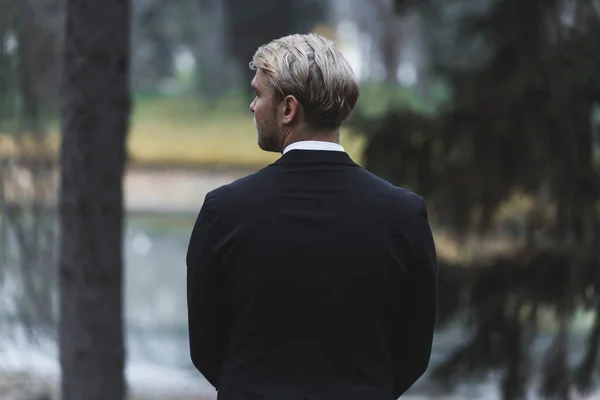 Rear view of well-build fit handsome blond Scandinavian man waiting for his bride. Outdoor forest autumn photoshoot. Marriage and life together. High quality photo
