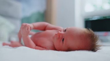Yeni doğmuş beyaz bir çocuk, yakın çevresini gözlemliyor ve duygularını el ve bacak hareketleriyle ifade ediyor. Bulanık Bakchrknd. Bebek konsepti. Yüksek kalite 4k görüntü