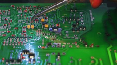 Modern elektrik cihazlarının temel bileşenleri. Yeşil baskılı devre kartına yapıştırılmış küçük parçaların elle montajı. Kafkas uzmanı cımbız kullanıyor. Yüksek kalite 4k görüntü