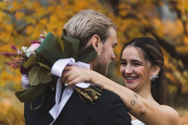 新婚夫妇的幸福 中东新娘拿着新鲜的花束 抱着她的丈夫 笑着的服装肖像 模糊的背景 金秋户外摄影 高质量的 — 图库照片