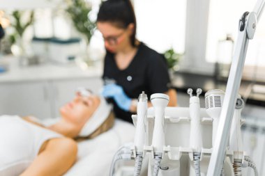 Farklı yüz bakımları için çeşitli kozmetik aletler kullanılıyor. Ön plana odaklan. Tanımlanamayan beyaz kadın güzellik uzmanı müşterilerinin yüzüne mikro dermabrüksiyon uyguluyor.