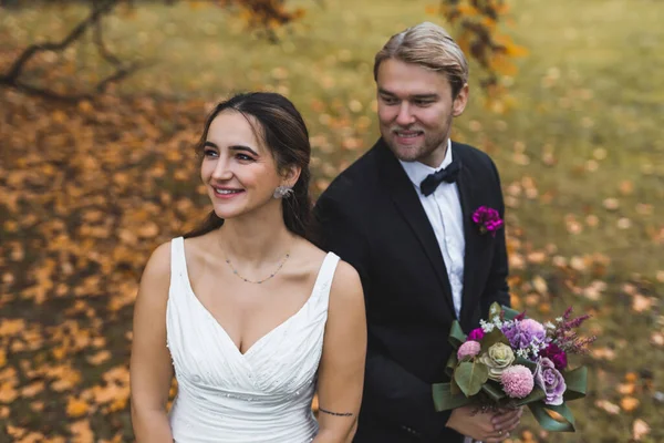 户外秋天的肖像 笑容满面的异性恋新婚夫妇穿着婚纱在美丽的秋天森林里摆出婚纱照 高质量的照片 — 图库照片
