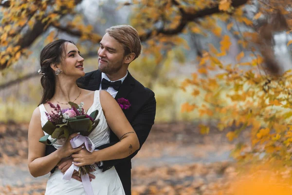 婚礼后拍照时 穿着婚纱的快乐的新婚夫妇站在秋天的森林或公园里 爱情和婚姻 中室外拍摄 高质量的照片 — 图库照片