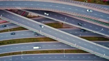 Hızlı giden araba ve kamyonlarla kavşağın hava görüntüsü, trafik yok. Trafik sıkışıklığını önlemek için yükseltilmiş yolların modern tasarımı. Yüksek kalite 4k görüntü