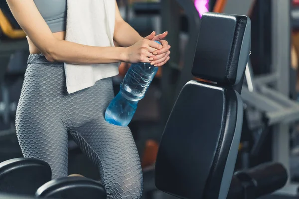 stock image Unknown, young, slim, caucasian woman wearing grey leggings and a top, holding a bottle of water on her lap and a white towel on her shoulder, standing in the gym. High quality photo