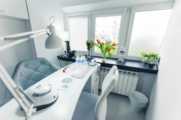 interior design of a nail studio, light room with light color furniture and flowers on the window-sill. High quality photo